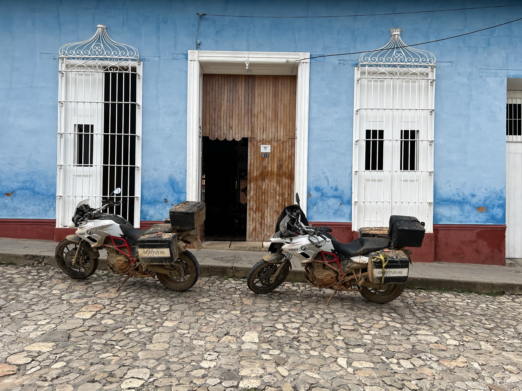 Adventure motorcycles parked outside a blue Havana building